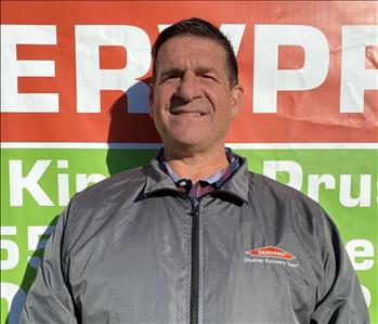 Male Employee Standing in front of SERVPRO Banner 